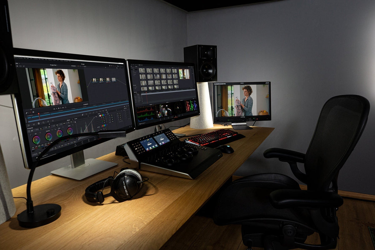 Grey painted walls surrounding a professional color grading suite with a Flanders monitor, DaVinci Resolve Mini Panel, and headphones.