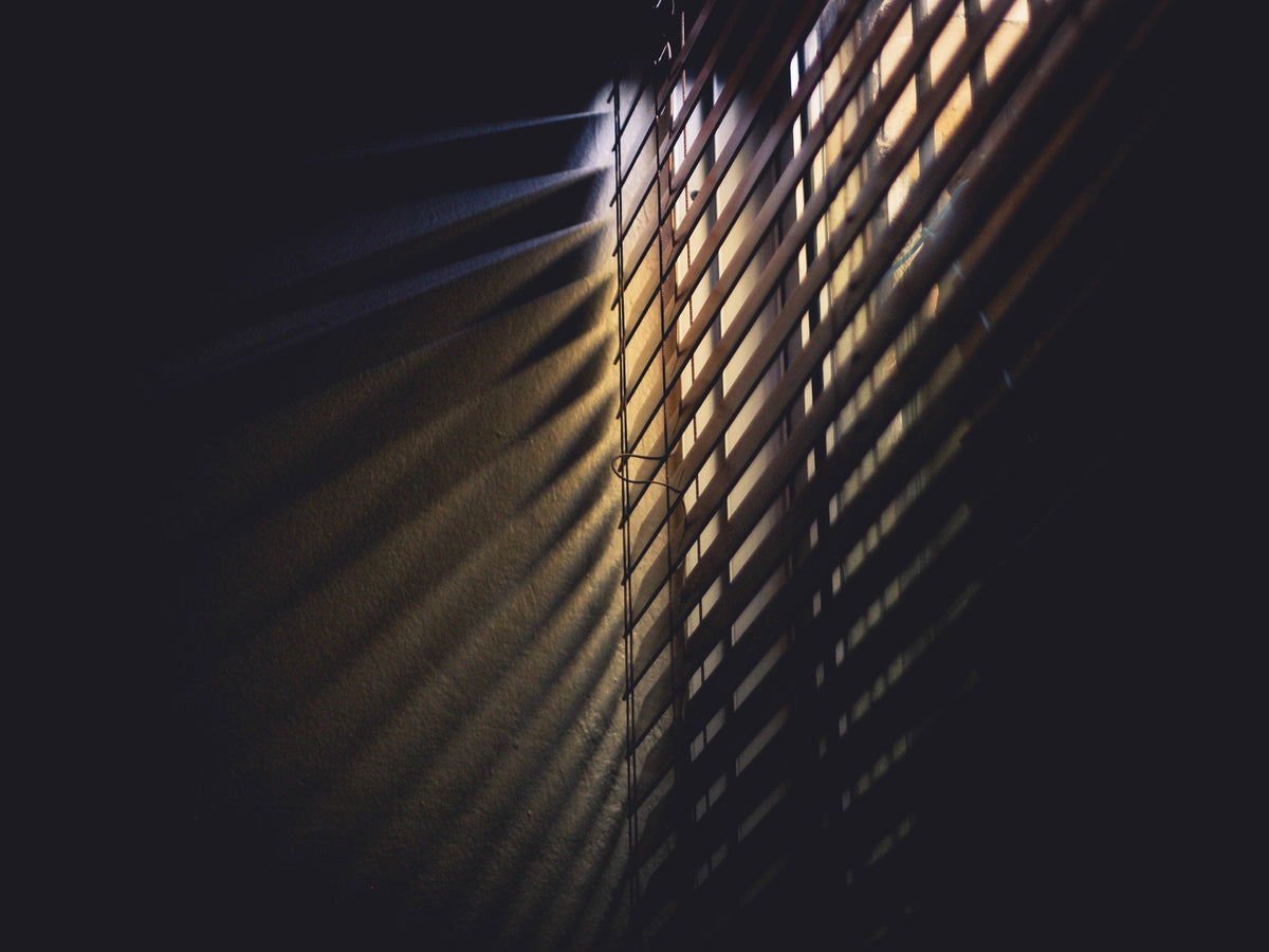 Sunlight falling through blinds onto a dark wall